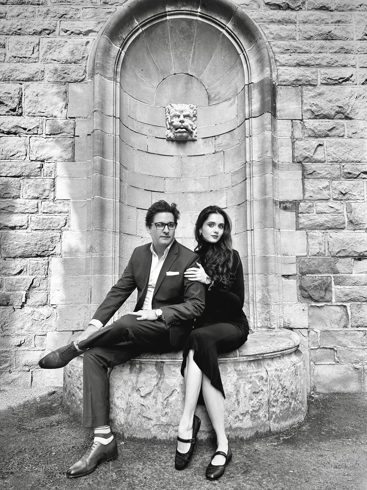 Christian and Paige seated together beneath a carved stone arch